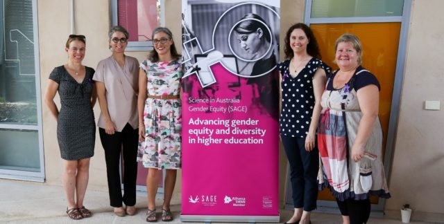 Photograph of five women standing next to a SAGE banner that reads "Advancing gender equity and diversity in higher education".
