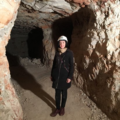 Annette Condello stands at cave entrance, wearing a hard hat.